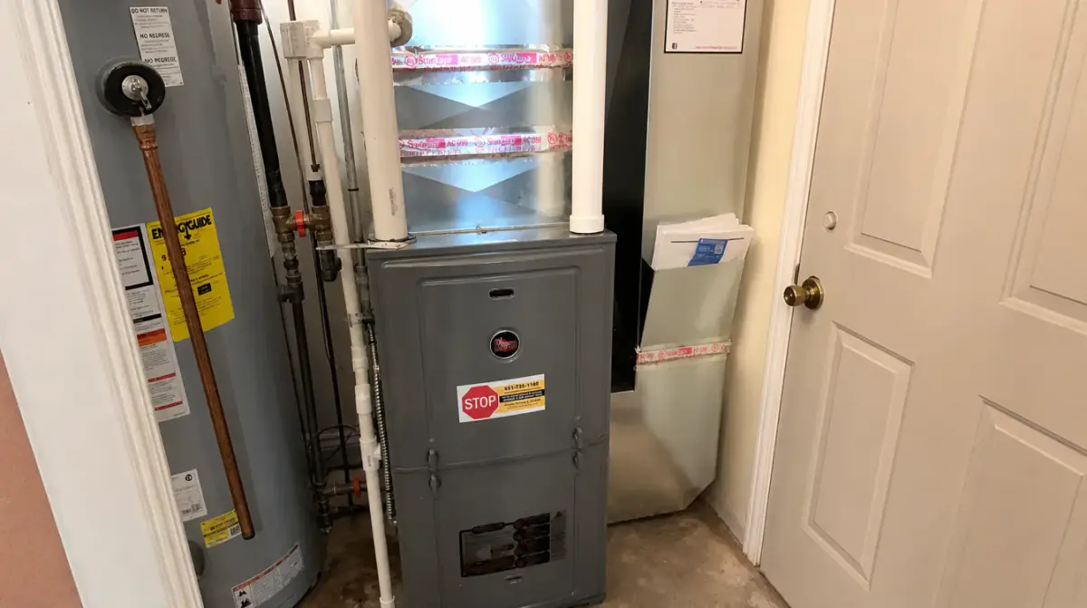 A high-efficiency furnace installed in a narrow utility closet next to a gas water heater